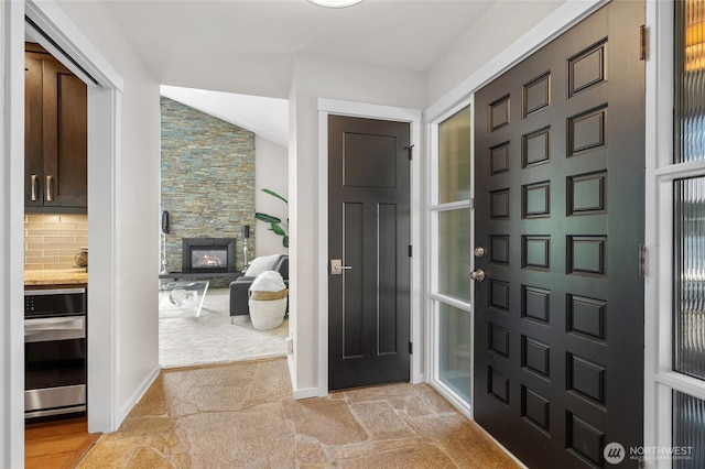 423 99th Ave NE Unit 6, Bellevue, WA 98004 - foyer entrance featuring a stone fireplace, lofted ceiling, and baseboards