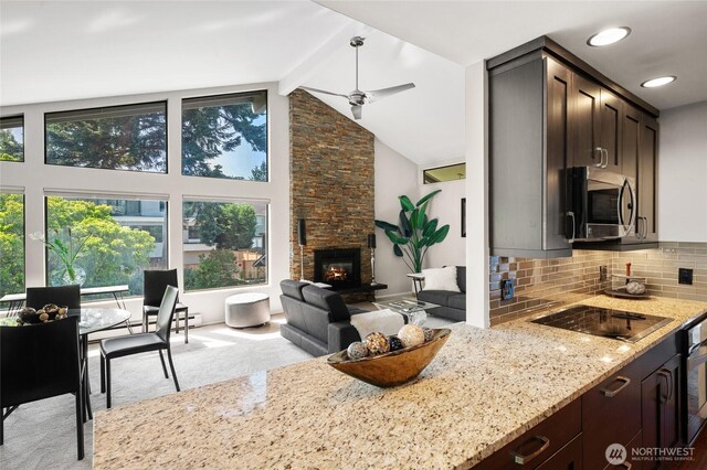 423 99th Ave NE Unit 6, Bellevue, WA 98004 - kitchen featuring stainless steel microwave, light stone countertops, black electric cooktop, dark brown cabinetry, and backsplash