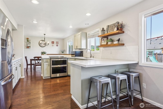 6413 152nd Ave E, Sumner, WA 98390 - kitchen featuring a peninsula, stainless steel appliances, a chandelier, light countertops, and dark wood-type flooring