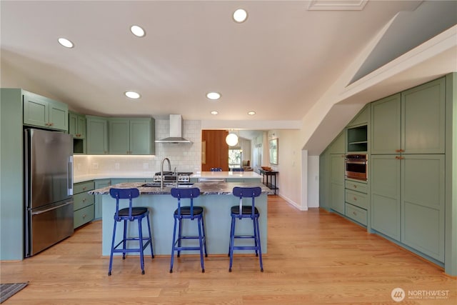 905 Bywater Way, Port Ludlow, WA 98365 - kitchen featuring stainless steel appliances, green cabinets, wall chimney range hood, recessed lighting, and vaulted ceiling