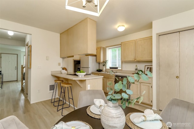 5129 Green Hills Ave NE Unit A, Tacoma, WA 98422 - kitchen featuring freestanding refrigerator, light brown cabinetry, a peninsula, light wood-style floors, and a breakfast bar area