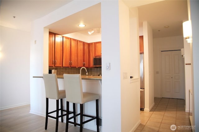 1900 Alaskan Way Unit 105, Seattle, WA 98101 - kitchen with appliances with stainless steel finishes, a kitchen bar, decorative backsplash, and baseboards