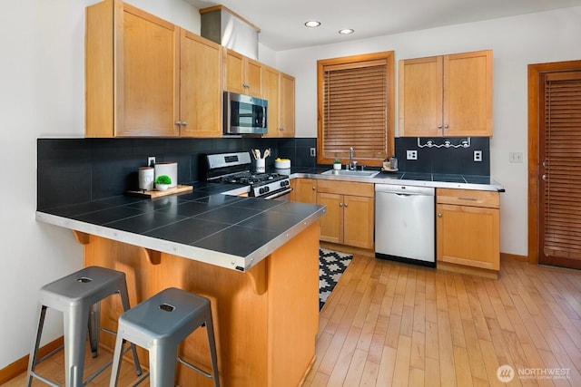 1414 25th Ave Unit B, Seattle, WA 98122 - kitchen with stainless steel appliances, a breakfast bar area, tile countertops, a peninsula, and backsplash