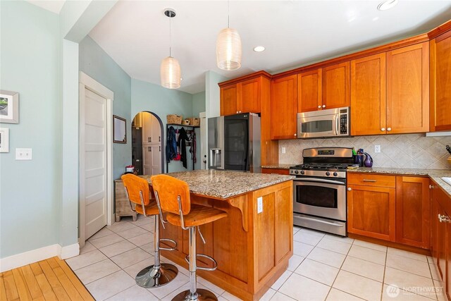 805 11th St, Bellingham, WA 98225 - kitchen with stainless steel appliances, brown cabinetry, decorative backsplash, light stone countertops, and recessed lighting