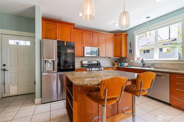 805 11th St, Bellingham, WA 98225 - kitchen with appliances with stainless steel finishes, a sink, light tile patterned floors, a center island, and light stone countertops