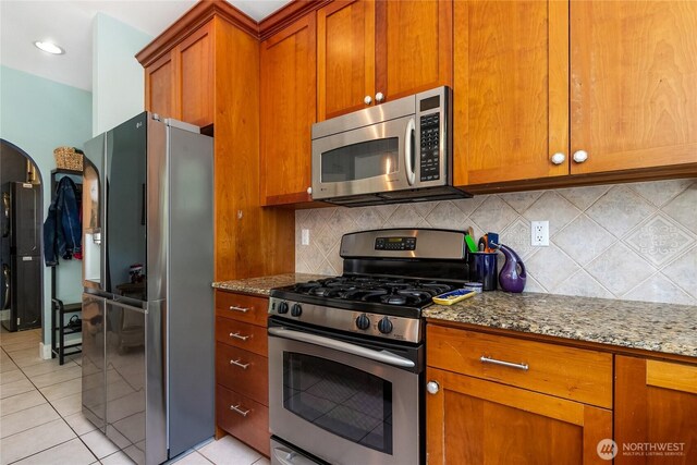 805 11th St, Bellingham, WA 98225 - kitchen with stainless steel appliances, stone countertops, brown cabinets, backsplash, and light tile patterned floors