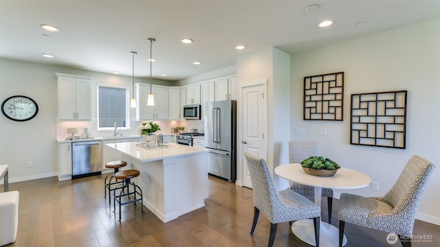 14528 35th Ave NE, Lake Forest Park, WA 98155 - kitchen featuring high quality appliances, a breakfast bar area, a center island, dark wood-type flooring, and white cabinetry