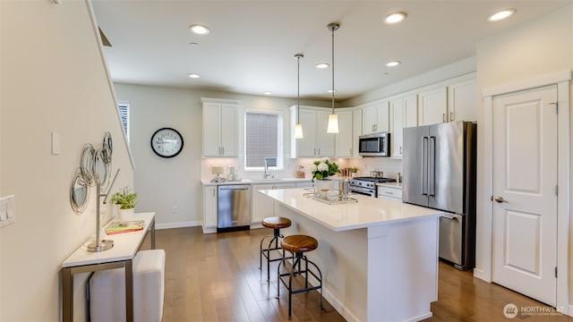 14528 35th Ave NE, Lake Forest Park, WA 98155 - kitchen with high quality appliances, a kitchen breakfast bar, white cabinetry, dark wood-type flooring, and pendant lighting