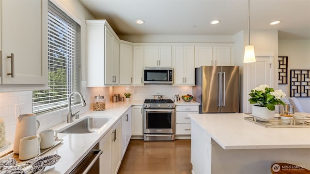 14528 35th Ave NE, Lake Forest Park, WA 98155 - kitchen with stainless steel appliances, white cabinetry, dark wood finished floors, backsplash, and decorative light fixtures