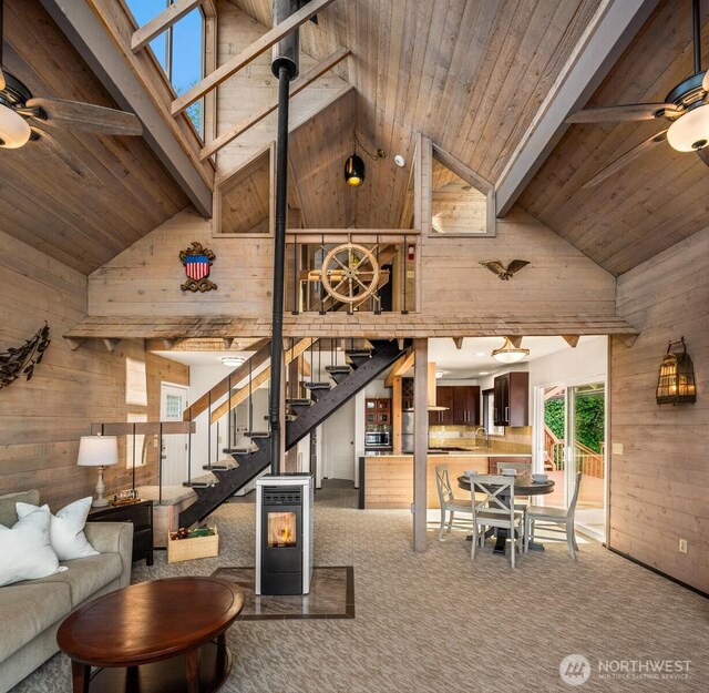 11901 Larson Rd, Anderson Island, WA 98303 - living room with high vaulted ceiling, wood walls, a ceiling fan, wooden ceiling with exposed beams, and stairway