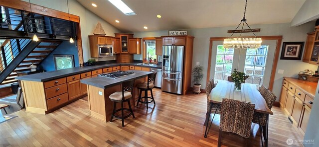 8145 Chehalis Rd, Blaine, WA 98230 - kitchen featuring stainless steel appliances, lofted ceiling, dark countertops, light wood-type flooring, and a chandelier