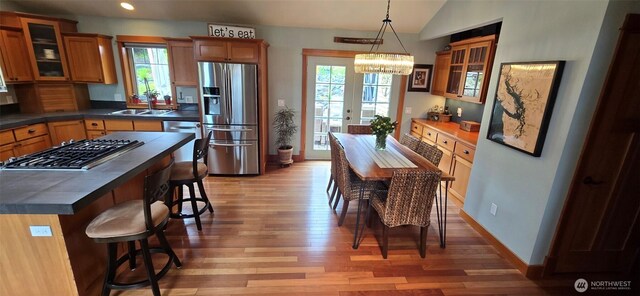 8145 Chehalis Rd, Blaine, WA 98230 - kitchen with stainless steel appliances, a sink, light wood finished floors, a kitchen breakfast bar, and brown cabinets