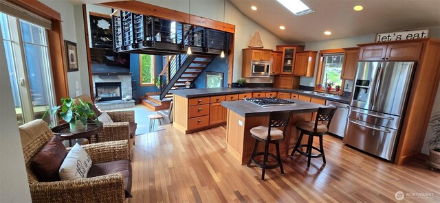 8145 Chehalis Rd, Blaine, WA 98230 - kitchen featuring stainless steel appliances, a peninsula, a sink, light wood finished floors, and a fireplace