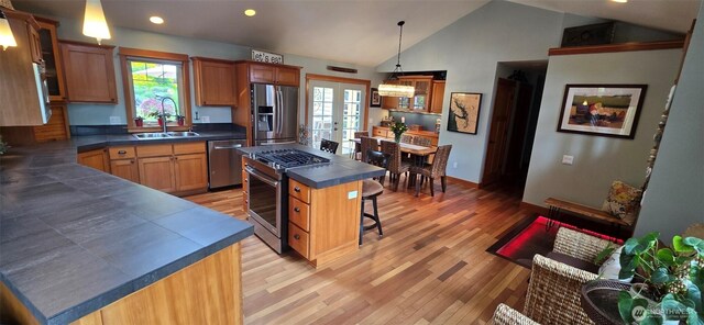 8145 Chehalis Rd, Blaine, WA 98230 - kitchen featuring appliances with stainless steel finishes, a sink, dark countertops, a kitchen breakfast bar, and light wood-style flooring