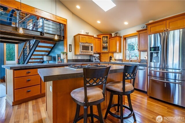 8145 Chehalis Rd, Blaine, WA 98230 - kitchen featuring appliances with stainless steel finishes, dark countertops, a center island, light wood finished floors, and vaulted ceiling