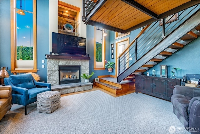 8145 Chehalis Rd, Blaine, WA 98230 - living area with stairway, wooden ceiling with exposed beams, carpet floors, and a stone fireplace