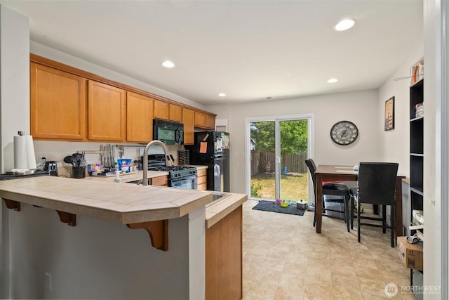 6600 Carolina St SE, Lacey, WA 98513 - kitchen with black appliances, a kitchen breakfast bar, tile counters, recessed lighting, and a peninsula