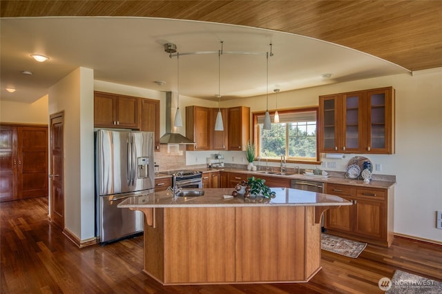 144 Sand Dune Ave SW, Ocean Shores, WA 98569 - kitchen featuring appliances with stainless steel finishes, wall chimney exhaust hood, brown cabinets, a sink, and a kitchen island with sink