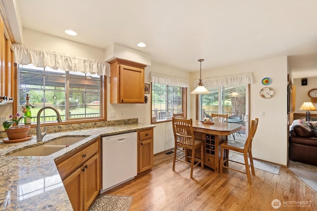 14406 144th St E, Orting, WA 98360 - kitchen with white dishwasher, a sink, light wood-style flooring, light stone counters, and brown cabinets