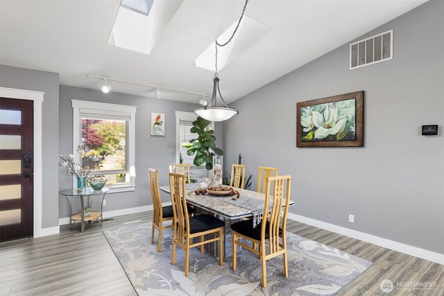 37981 Hood Canal Dr NE, Hansville, WA 98340 - dining space with wood finished floors, a skylight, baseboards, track lighting, and vaulted ceiling
