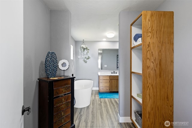 37981 Hood Canal Dr NE, Hansville, WA 98340 - bathroom with a soaking tub, vanity, wood finished floors, and baseboards