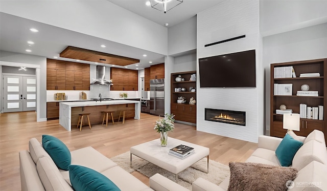1542 213th Ct NE, Sammamish, WA 98074 - living room featuring a large fireplace, light wood-style flooring, recessed lighting, french doors, and a high ceiling