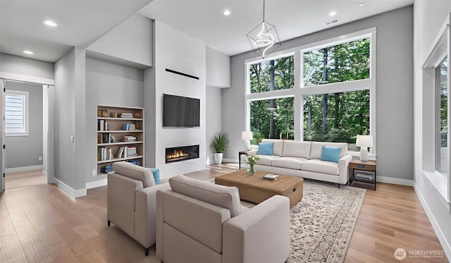 1542 213th Ct NE, Sammamish, WA 98074 - living room with baseboards, a fireplace, light wood-type flooring, a towering ceiling, and recessed lighting