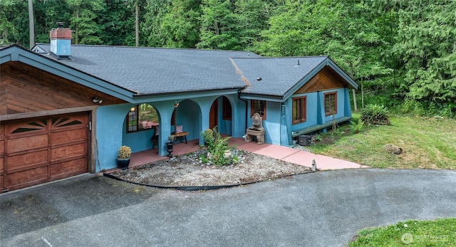 70 Cole Ave, Port Townsend, WA 98368 - view of front of home with roof with shingles, a chimney, driveway, stucco siding, and covered porch