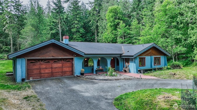 70 Cole Ave, Port Townsend, WA 98368 - ranch-style home featuring asphalt driveway, a garage, a chimney, and a forest view