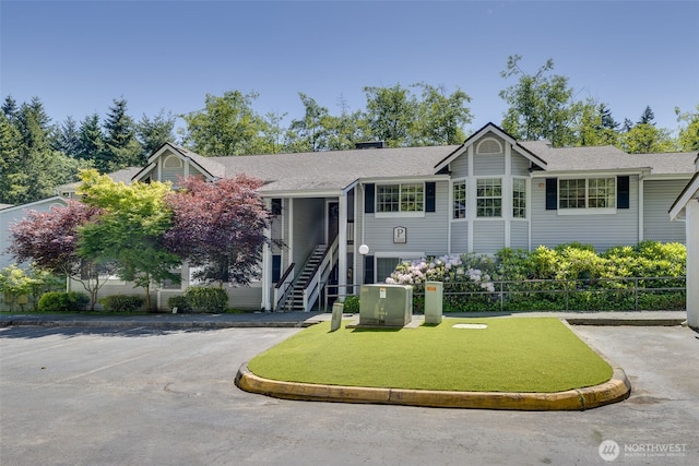 23311 Cedar Way Unit P201, Mountlake Terrace, WA 98043 - view of front of home featuring uncovered parking, roof with shingles, stairs, and a chimney
