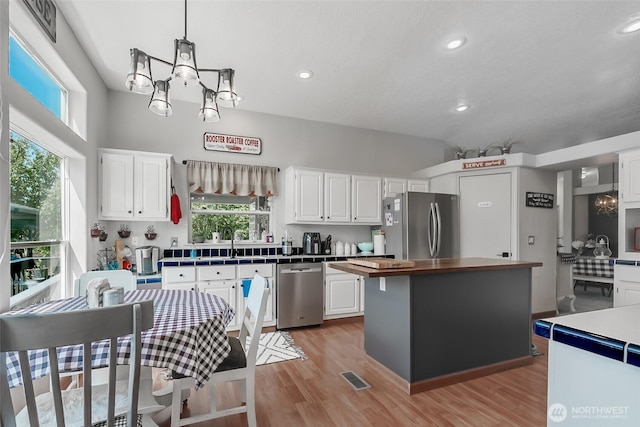 10419 Sandridge Rd, Long Beach, WA 98631 - kitchen with stainless steel appliances, a chandelier, white cabinetry, light wood-style floors, and recessed lighting