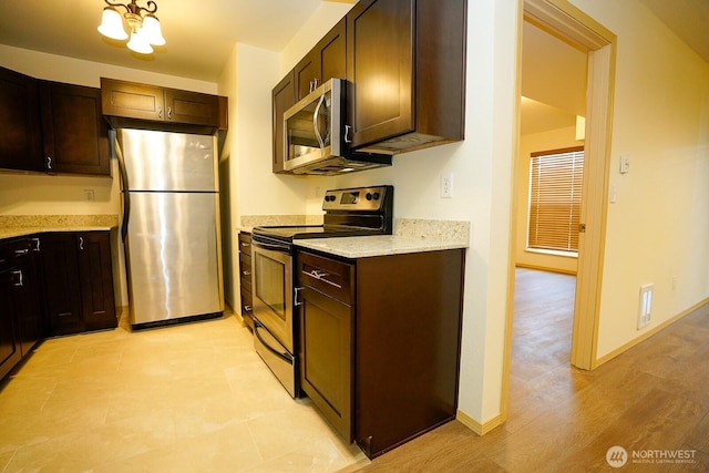 1031 N State St Unit 402, Bellingham, WA 98226 - kitchen featuring stainless steel appliances, dark brown cabinetry, light stone counters, baseboards, and light wood-style floors