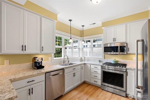 1747 Parade Grounds Ave NE, Bainbridge Island, WA 98110 - kitchen with stainless steel appliances, white cabinetry, decorative light fixtures, light wood finished floors, and light stone countertops