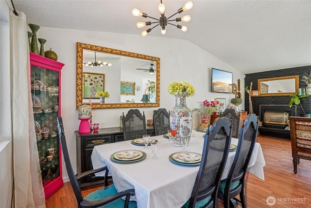 29103 46th Pl S, Auburn, WA 98001 - dining space with a chandelier, vaulted ceiling, wood finished floors, a brick fireplace, and a textured ceiling