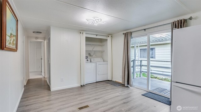 1510 Maple Ln Unit 16, Kent, WA 98030 - laundry room with light wood-type flooring, washing machine and clothes dryer, baseboards, and a textured ceiling