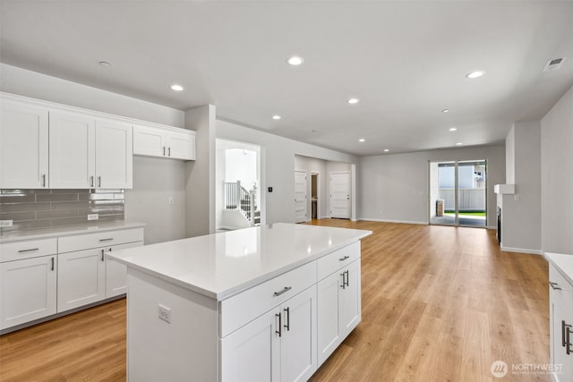 16617 8th Avenue Ct E Unit 9, Spanaway, WA 98387 - kitchen featuring light countertops, white cabinets, a kitchen island, light wood-style floors, and decorative backsplash