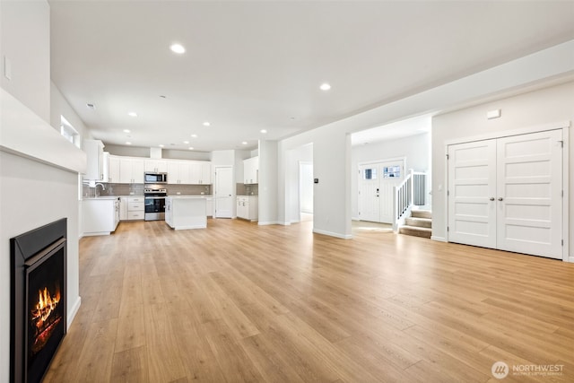 16617 8th Avenue Ct E Unit 9, Spanaway, WA 98387 - unfurnished living room featuring light wood-style flooring, a lit fireplace, stairway, and recessed lighting