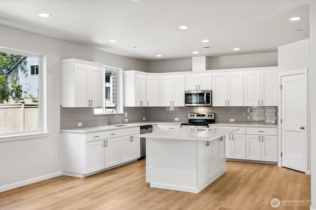 16617 8th Avenue Ct E Unit 9, Spanaway, WA 98387 - kitchen with appliances with stainless steel finishes, light countertops, white cabinetry, backsplash, and light wood-type flooring