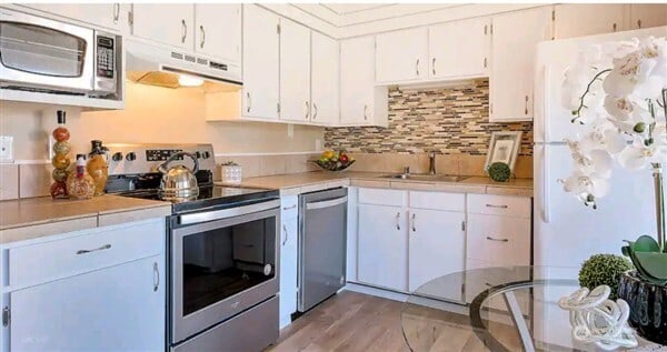 7530 Birch Bay Dr Unit 206, Blaine, WA 98230 - kitchen featuring appliances with stainless steel finishes, under cabinet range hood, white cabinetry, and a sink