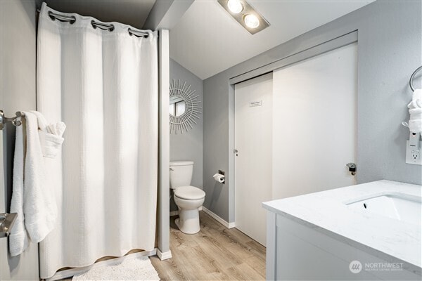 7530 Birch Bay Dr Unit 206, Blaine, WA 98230 - full bath featuring vanity, toilet, wood finished floors, curtained shower, and vaulted ceiling