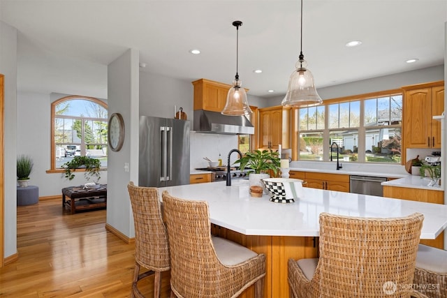 367 E Silverado Ct, Bellingham, WA 98226 - kitchen featuring extractor fan, stainless steel appliances, light countertops, light wood-style flooring, and a center island with sink
