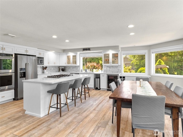 34214 102nd Ave S, Roy, WA 98580 - kitchen with appliances with stainless steel finishes, wine cooler, white cabinetry, tasteful backsplash, and light wood-style flooring