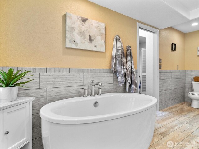 34214 102nd Ave S, Roy, WA 98580 - full bath featuring tile walls, a freestanding bath, wood finished floors, toilet, and a wainscoted wall