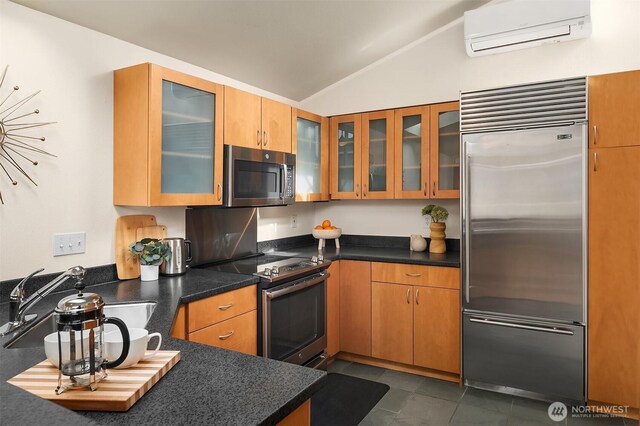 2420 Westlake Ave N Unit 11, Seattle, WA 98109 - kitchen with appliances with stainless steel finishes, a wall mounted air conditioner, vaulted ceiling, glass insert cabinets, and dark countertops