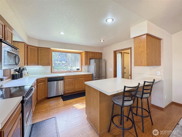 42 Charles Way, Sequim, WA 98382 - kitchen with appliances with stainless steel finishes, light wood-style floors, a sink, a kitchen bar, and recessed lighting