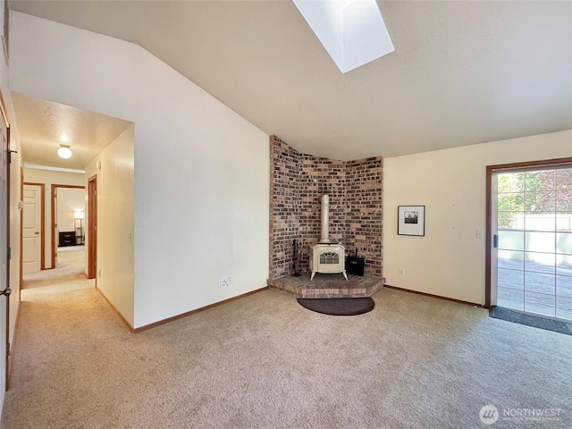 42 Charles Way, Sequim, WA 98382 - unfurnished living room featuring a wood stove, carpet floors, vaulted ceiling, a skylight, and baseboards