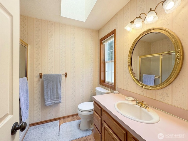42 Charles Way, Sequim, WA 98382 - full bathroom featuring a skylight, toilet, wood finished floors, vanity, and a shower with door
