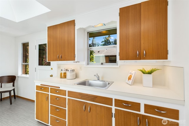 7008 25th Ave NE, Seattle, WA 98115 - kitchen with a sink, light countertops, a skylight, and brown cabinetry