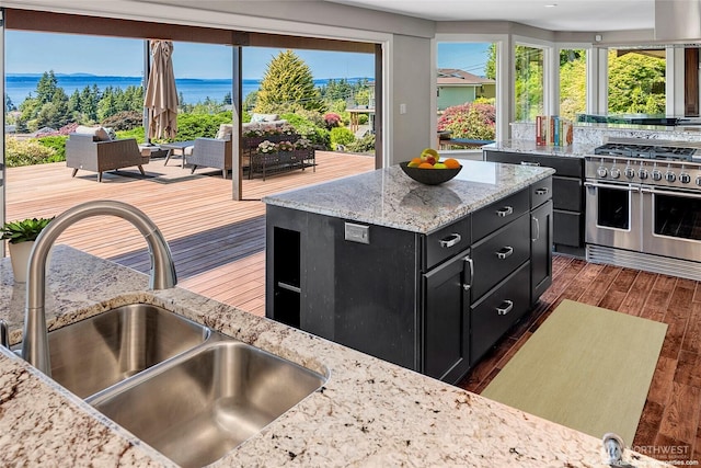 926 Olympic Ave, Edmonds, WA 98020 - kitchen featuring dark cabinetry, range with two ovens, dark wood finished floors, light stone counters, and a kitchen island