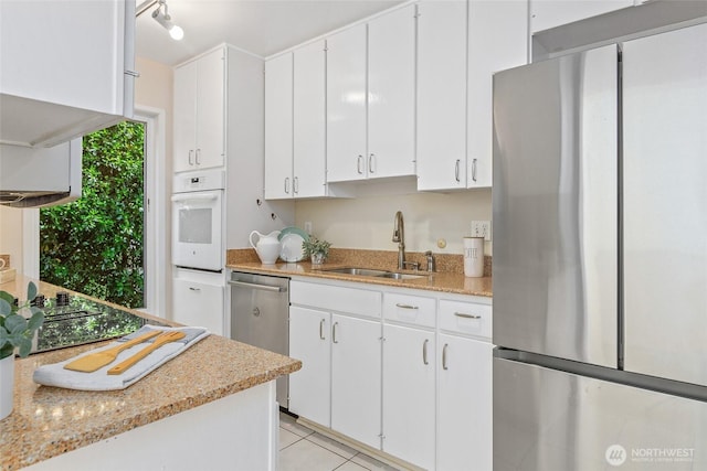 101 NW 58th St Unit 9, Seattle, WA 98107 - kitchen with stainless steel appliances, a sink, white cabinets, light stone counters, and light tile patterned floors